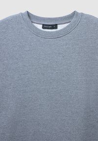 Felpa grigia chiara con colletto a girocollo, caratterizzata da una texture glitterata sottile e un collo a costine, etichettata come taglia piccola dal marchio Calliope.