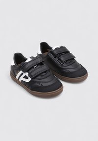 Zapatos negros con una combinación de cuero texturizado y malla, que presentan dos tiras de Velcro, una suela de goma marrón y un acento blanco.