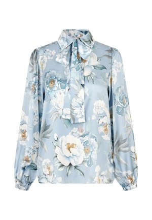 Blouse à manches longues bleu clair avec motif floral blanc et vert, dotée d'un col montant et d'un grand nœud à la base du col.
