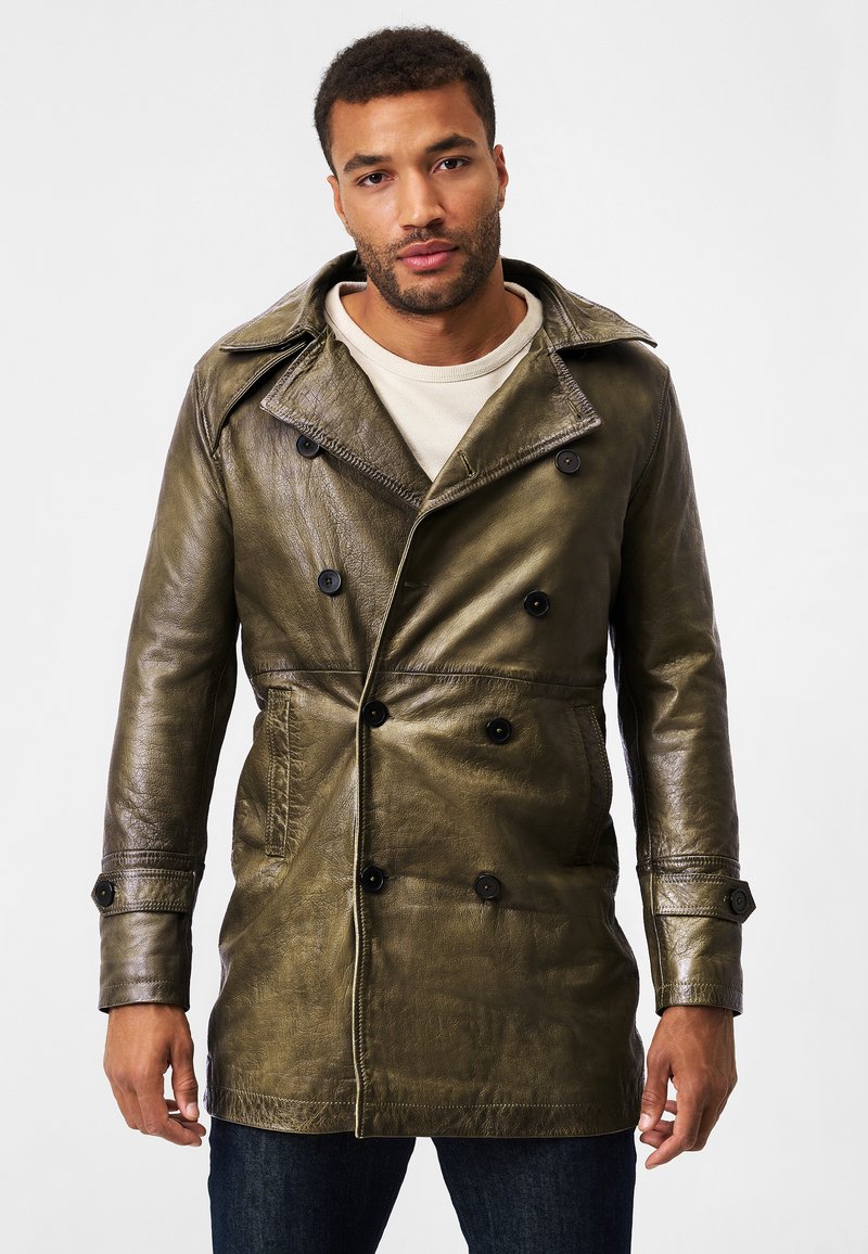 Olive green leather trench coat with a double-breasted design, large lapels, black buttons, and side pockets, worn over a light shirt.