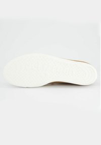 Suola in gomma bianca con superficie testurizzata, caratterizzata da un design pulito e bordi arrotondati. Il materiale superiore di un beige chiaro è visibile sui lati.