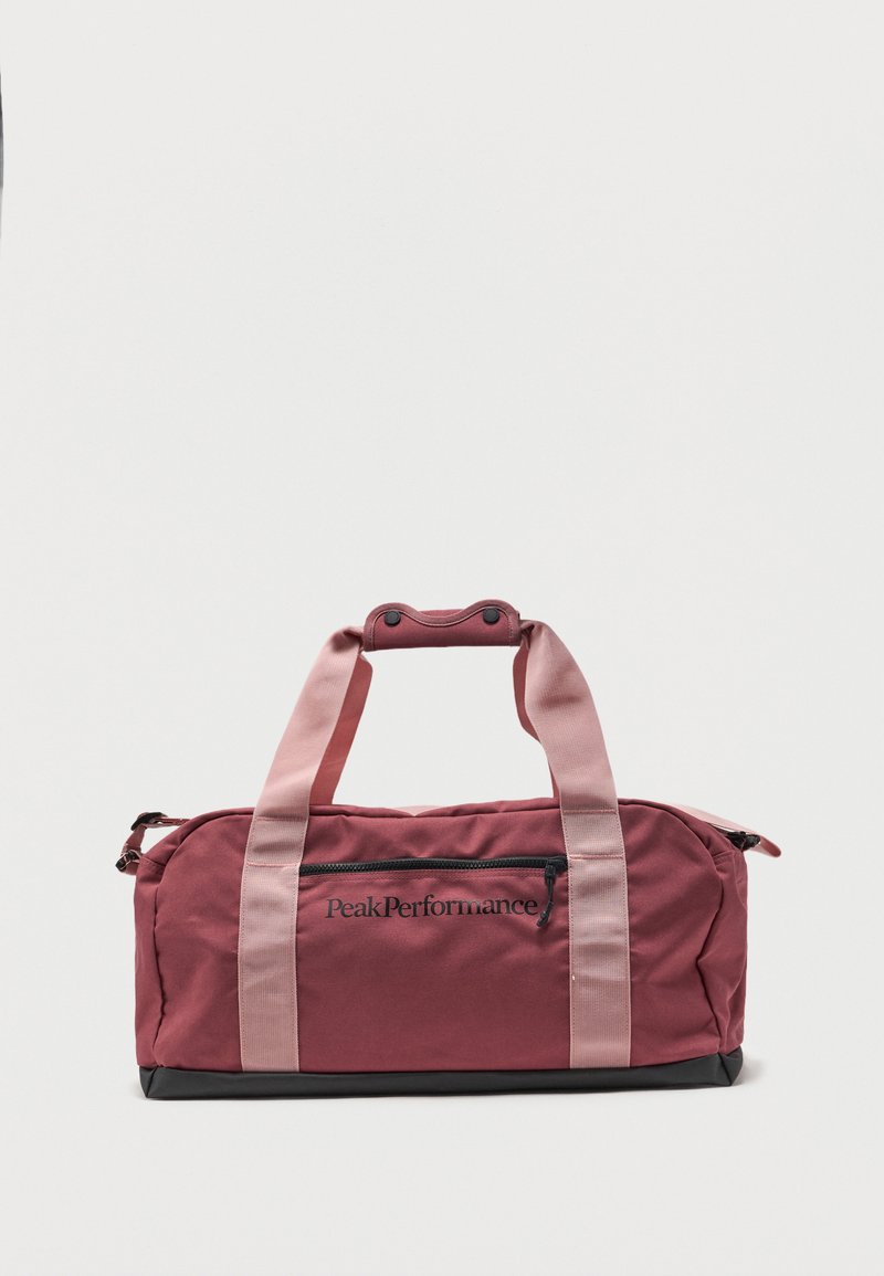 Τσάντα duffel Peak Performance σε μαροον και ροζ χρώμα με δύο λαβές, εμπρόσθια τσέπη με φερμουάρ και μαύρη βάση, τοποθετημένη σε λευκό φόντο.