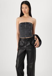 Top sans bretelles en denim gris avec fermeture éclair à l'avant, associé à un pantalon en cuir noir taille haute et un sac noir. Texture lisse, design ajusté.