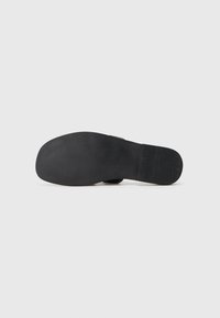 Black rubber shoe sole with a textured surface and slight grooves for grip. Flat design with no visible branding or embellishments.
