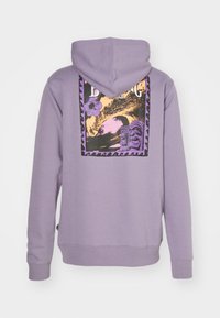 Fialová mikina s grafickým potlačou na chrbte znázorňujúcim vlnu, tiki postavy a kvet, vyrobená z mäkkej zmesi bavlny.