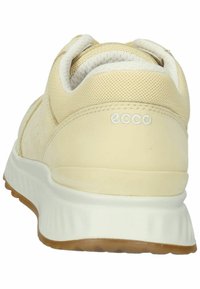 Light yellow sneaker with a smooth leather and mesh upper, white midsole, and textured rubber outsole featuring a subtle logo on the heel.