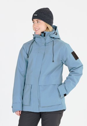 Helle blaue wasserdichte Jacke mit hohem Kragen, verstellbarem Kapuze, zwei Vordertaschen und schwarzen Logoakzenten an den Ärmeln. Warme gestrickte dunkelgraue Mütze.