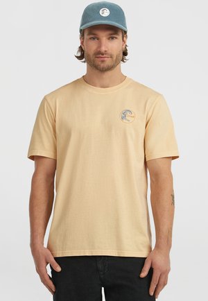 Light peach cotton T-shirt featuring short sleeves and a round neck, with a circular logo in blue and orange on the left chest area.