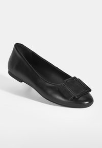 Schwarze Leder-Ballerinas mit einer abgerundeten Spitze, die ein auffälliges schwarzes Wildleder-Schnallen-Accessoire im Vorfußbereich und eine glatte, strukturierte Oberfläche aufweisen.
