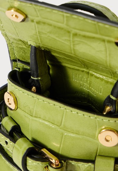 Mala de mão em pele texturizada de crocodilo verde com pega preta, ferragens douradas e "Moschino Milano Made in Italy" estampado no interior.