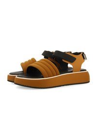 Sandalias de plataforma marrones y negras con un diseño de tiras acolchadas y acolchonadas, y hebilla ajustable en el lateral. Fabricadas en material sintético.