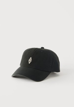 Casquette de baseball noire avec un petit logo géométrique argenté sur le devant, présentée sur un fond uni clair.