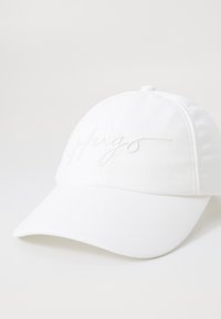 Cappellino in cotone bianco con logo "Hugo" ricamato in filo abbinato, con visiera curvata e design strutturato.