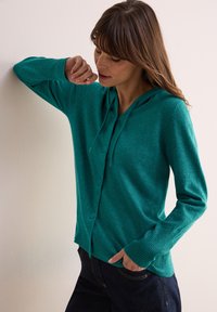 Teal gebreide cardigan met een capuchon, knopen sluiting en geribbelde manchetten. Zachte textuur, lichtgewicht materiaal en een ontspannen pasvorm.