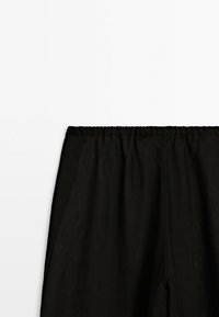 Black pants with an elastic waistband, shown from the waist down against a plain white background. No visible people or additional objects.