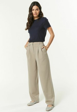 Haut bleu marine à manches courtes avec un col rond, associé à un pantalon large taille haute beige, doté de deux poches latérales.
