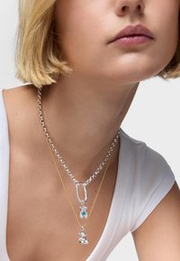 Naszyjniki z warstwą srebra i złota posiadają masywny łańcuch, zapięcie typu karabińczyk oraz charms w kształcie ananasa i niedźwiedzia.