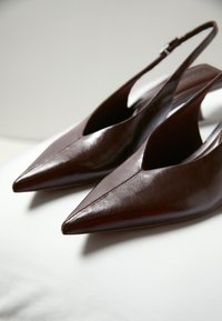 Escarpins slingbacks à bout pointu en cuir marron foncé avec talons carrés bas, présentés sur une surface claire.