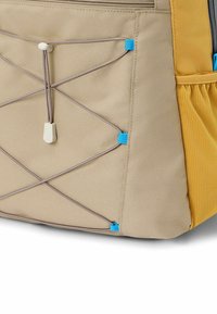Beige stof tas met gele accenten, voorzien van een bungee koord systeem in blauw. Zijnetzak voor extra opbergruimte. Getextureerd oppervlak.