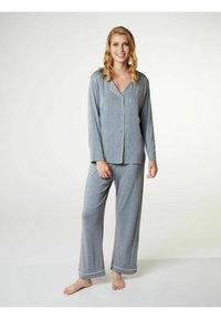 Completo pigiama grigio con una camicia con bottoni e pantaloni lunghi. Presenta piping bianco a contrasto lungo il colletto e i polsini. Tessuto morbido.