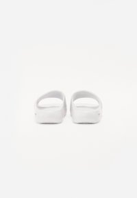 White clogs with an open-back design, smooth texture, and rounded shapes. Lightweight material with a contoured footbed.