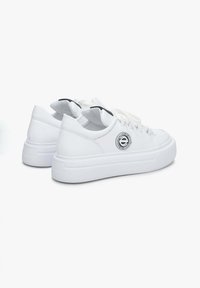 Witte sneakers met een glad leren bovenwerk, ronde neus, vlakke witte zool, zwarte accenten op de tong en een cirkelvormig logo detail aan de zijkant.