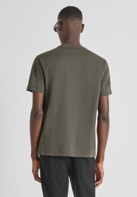 Olijfgroene T-shirt met korte mouwen van katoen, met een ronde halslijn en een relaxte pasvorm, een effen achterkant en een minimalistisch ontwerp.