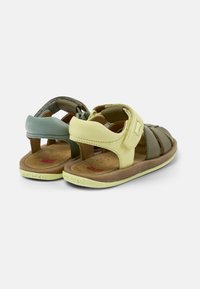 Två par barns sandaler med gröna, gula och bruna läderremmar, öppen tå-design och vadderad sula.