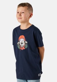 Tummansininen puuvillapaita, jossa on graafinen kuva koirasta punaisessa hatussa ja kuulokkeissa. Lyhyet hihat ja pyöreä kaula-aukko.