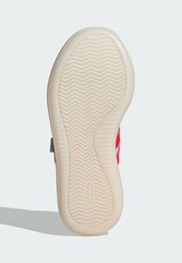 Skosula i ljusbrun gummi med horisontella ränder och ett fiskbensmönster. Har en ovandel med röd och blå design.