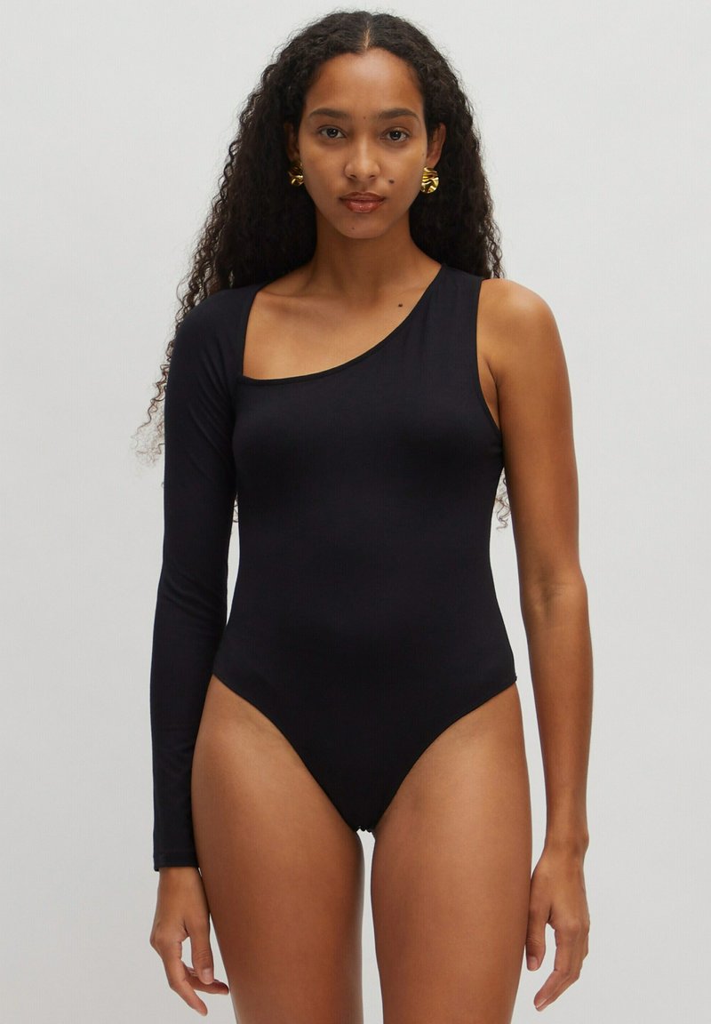 Zwarte badpak met asymmetrisch ontwerp; heeft één lange mouw en één schouderuitsnijding. Gladde, rekbare stof; minimalistische stijl.