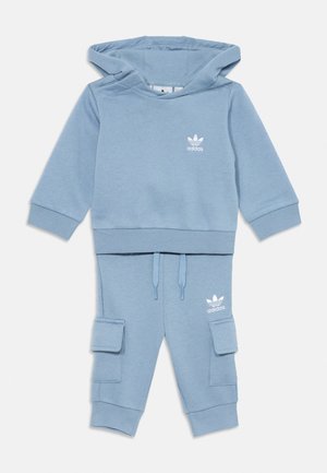 Svetlo modra otroška Adidas kapuca in cargo trenirka s belim logotipom na prsih in stegnu, pas z vrvico in obrobljeni rokavi in gležnji.