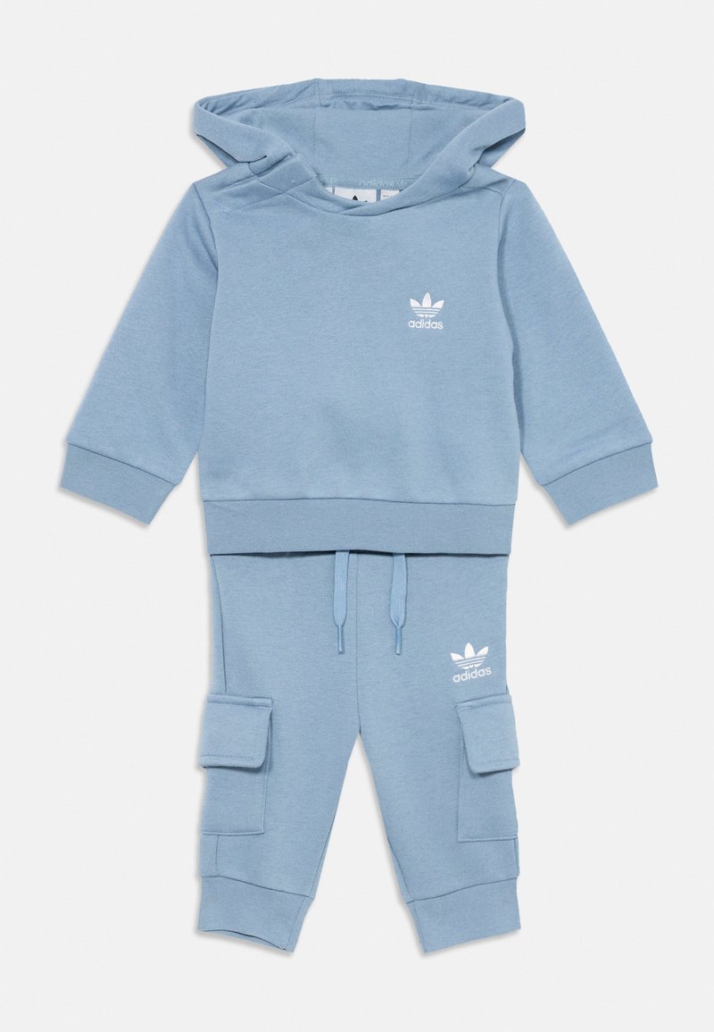 Ljusblå hoodie för småbarn från Adidas och ett set med cargo joggers med vitt logotyp på bröstet och låret, dragsko i midjan, samt mudd vid ärmar och anklar.