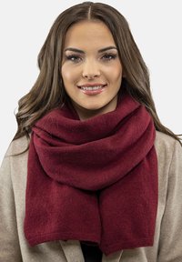 Bordeaux scarf lavet af blødt materiale, med en tykkere strikket tekstur. Bærer den løst om halsen, og den falder graciøst.
