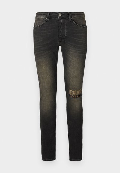 Black denim jeans with a slightly faded finish, a ripped detail on the knee, and embroidered "KSL" design with animal print accents.