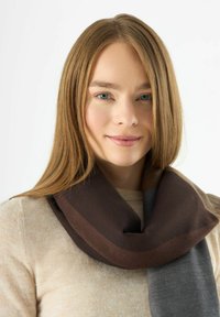 Sciarpa marrone e grigia, realizzata in un tessuto morbido, presenta un design ampio con colori sovrapposti, drappeggiata elegantemente attorno al collo.