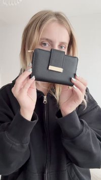 Zwarte faux leren portemonnee met een gestructureerd oppervlak, met een gouden accent en een eenvoudig ontwerp. Compacte en rechthoekige vorm.