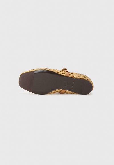 Talpa de încălțăminte plată cu o parte superioară din paie țesut, curea din piele maro și bază din cauciuc închis. Suprafață texturată cu un design elegant împletit.
