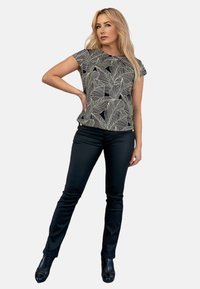 Czarny i biały top z wzorem liści i krótkim rękawem, zestawiony z dopasowanymi czarnymi spodniami i czarnymi botkami na obcasie, prezentujący elegancki, codzienny look.