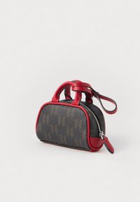 Kis sötétbarna kézitáska piros fogantyúkkal és díszítéssel, finom geometriai mintákkal, cipzáros záródással és hurok pánttal.