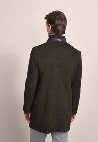 Dark brown coat with a textured fabric, a high collar, and contrasting inner lining. Features a tailored fit and a knee-length design.