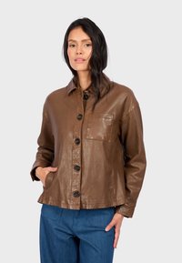 Camicia-giacca in pelle marrone con colletto, bottoni frontali e tasca sul petto. Presenta una vestibilità comoda e una texture liscia.
