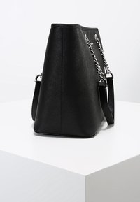 Borsa nera con finitura strutturata, design angolare e dettagli in catena d'argento. Dotata di tracolla rimovibile per una maggiore versatilità.