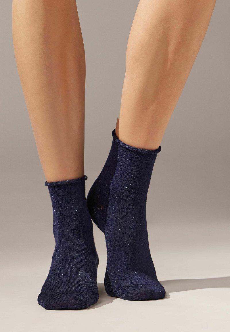 Calcetines tobilleros de color azul marino, fabricados con un tejido suave y brillante, con un puño acanalado y una textura lisa, diseñados para un uso cómodo.