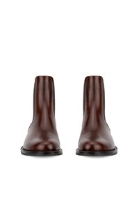 Een paar gepolijste donkerbruine leren Chelsea boots met zwarte zolen, voorkant weergegeven op witte achtergrond.