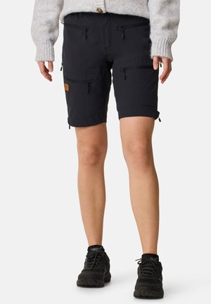 Black cargo shorts featuring multiple zippered pockets, adjustable cuffs, and a textured fabric. Paired with black athletic shoes.