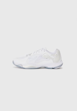 White athletic shoe with mesh panels, textured rubber outsole, and a transparent heel. Features a prominent logo on the side.