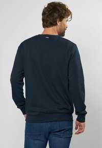 Dunkelblauer Sweatshirt mit Rundhalsausschnitt, gerippten Bündchen und Saum. Verfügt über eine glatte Stofftextur und einen kleinen gestreiften Akzent am Hals.