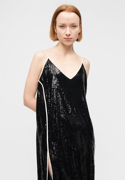 Μαύρο φόρεμα με παγιέτες, βαθύ V με λαιμόκοψη, λεπτές τιράντες και πλευρικές σχισμές. Διαθέτει υφή σαν σατέν με αντίθετες άσπρες λεπτομέρειες.