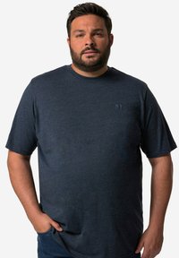 Mørkeblå kortærmet T-shirt i et blødt, struktureret stof med et subtilt logo på brystet, parret med blå denimjeans.